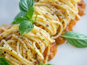 vegan pasta dish in Italy topped with black pepper and basil on a white plate