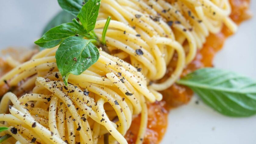 vegan pasta dish in Italy topped with black pepper and basil on a white plate