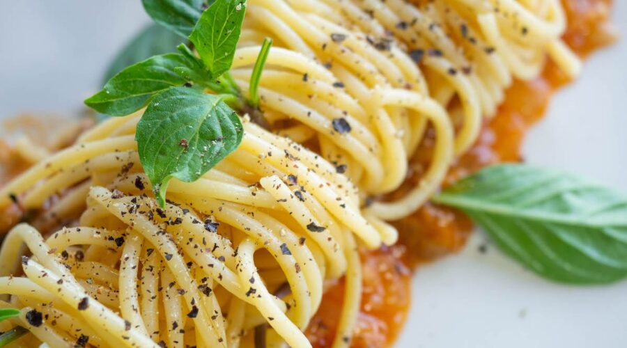 vegan pasta dish in Italy topped with black pepper and basil on a white plate