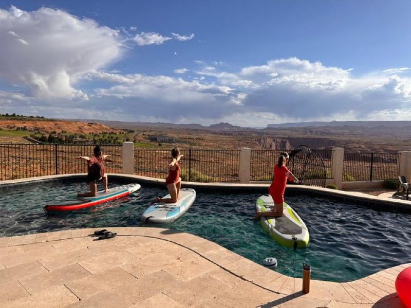 three people doing stand up paddleboarding in a pool during a vegan yoga retreat