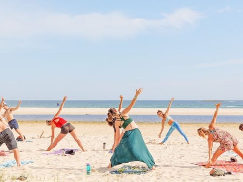 group of people doing yoga on the beach during a vegan yoga retreat