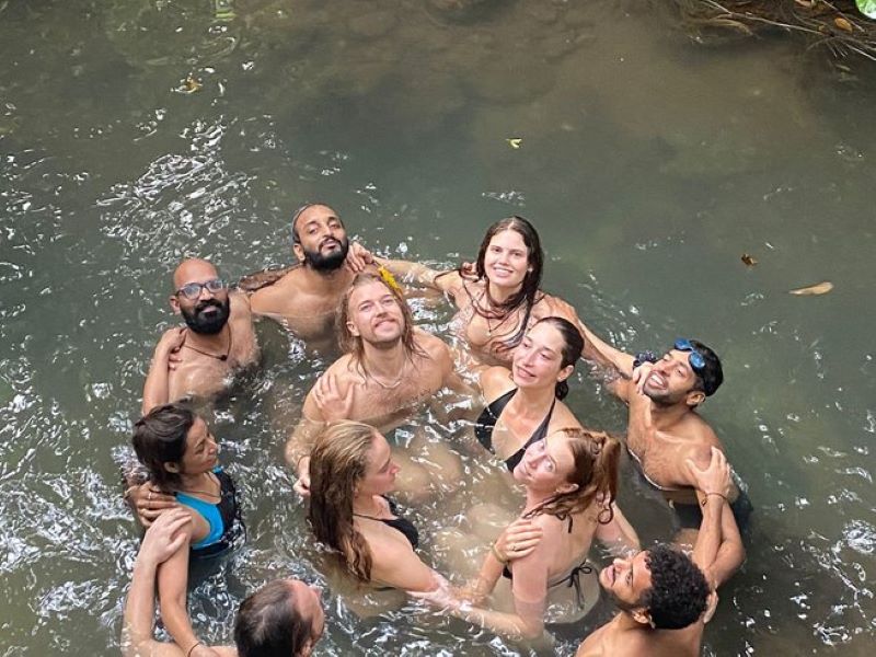 group of people holding hands in a circle while standing in water