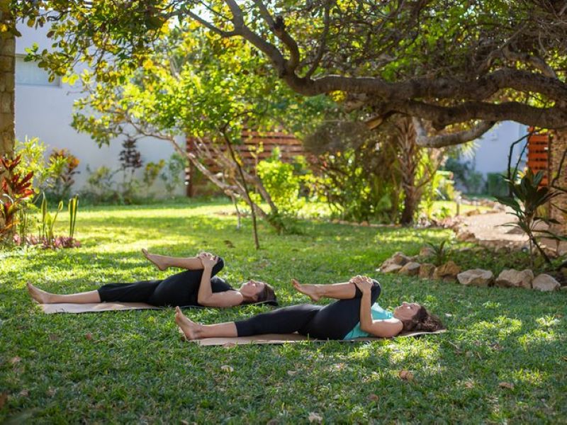 two women stretching on yoga mats in the grass