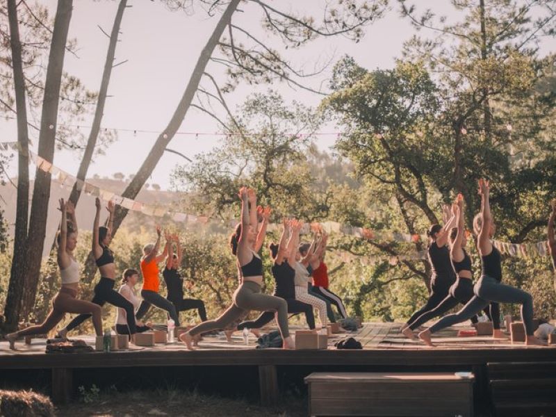 people on an outdoor wooden platform in high lunge pose