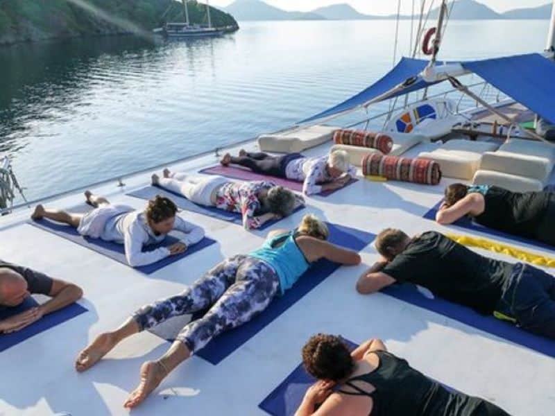 group of people laying on yoga mats on a boat deck