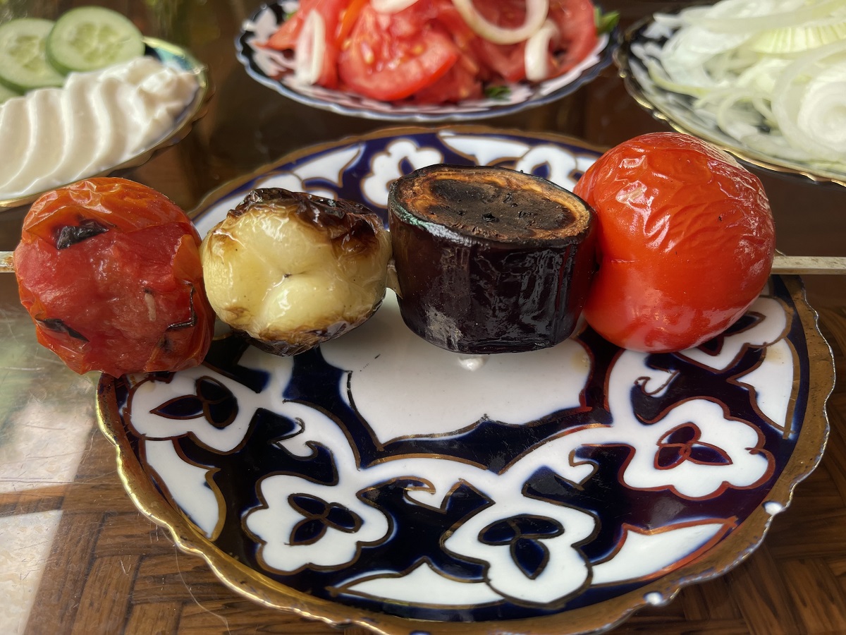 Delicious grilled vegetable skewers served at a vegetarian restaurant in Uzbekistan, featuring charred tomatoes, peppers, and eggplant. A tasty and colorful example of vegetarian options available in Uzbek cuisine.