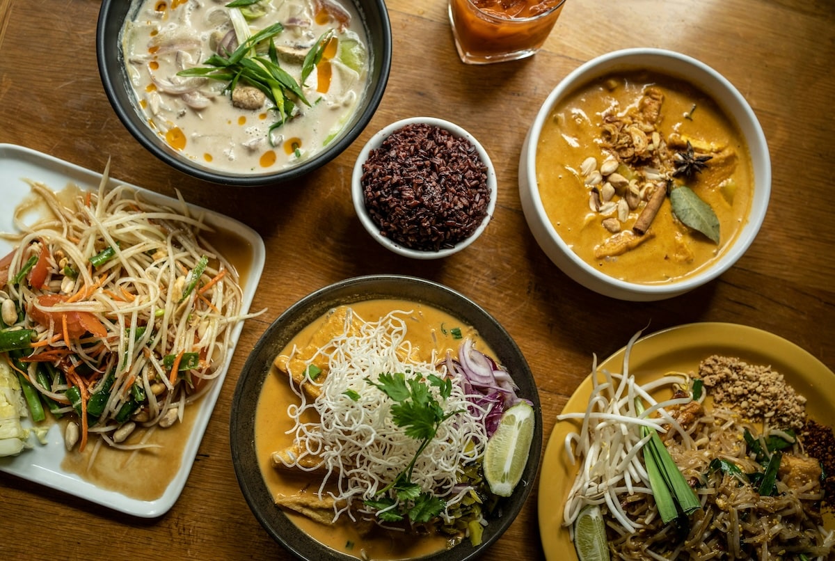 wooden table showcasing a variety of vegan Northern Thai dishes