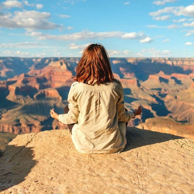 Woman meditating on a cliff on a solo retreat