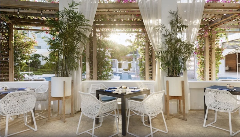 outdoor dining room with white chairs and curtains where they serve vegan meals at the Wymara Resort and Villas