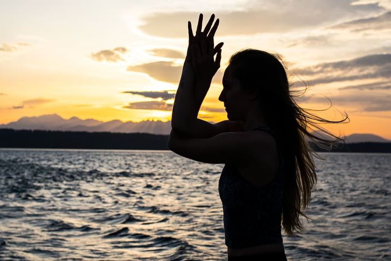 woman doing yoga on the beach at sunset