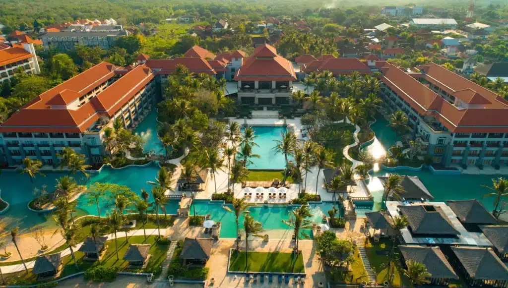 pools, palm trees, and buildings with orange roofs at the Conrad Bali Hotel